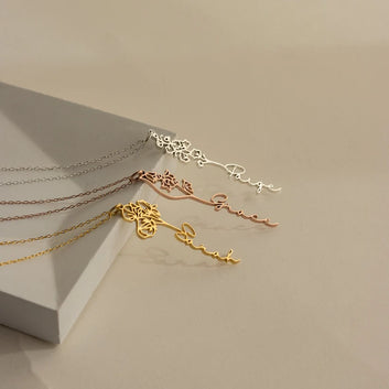 Three gold necklaces of different designs on a light gray surface