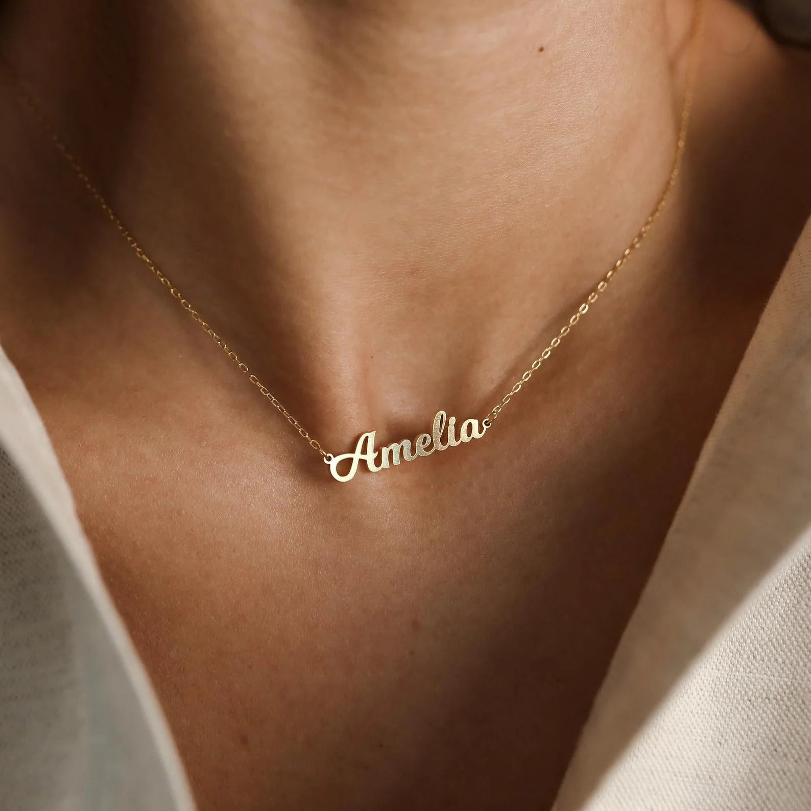 Gold necklace with 'Amelia' pendant on a person's neck