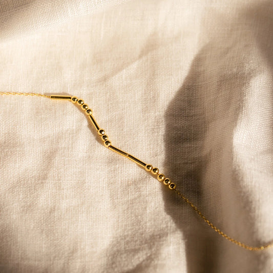 Gold necklace on a beige fabric background