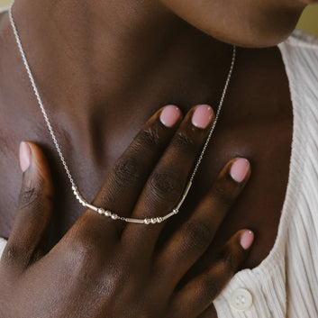 Necklace being worn with a hand resting on the chest