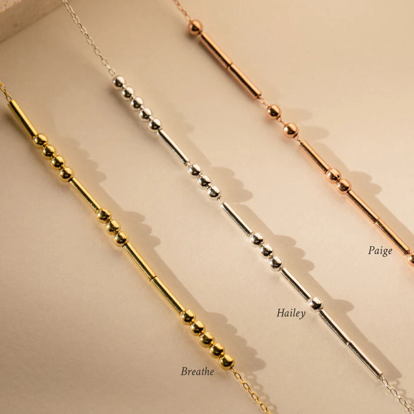 Three gold necklaces with different chain designs on a beige background