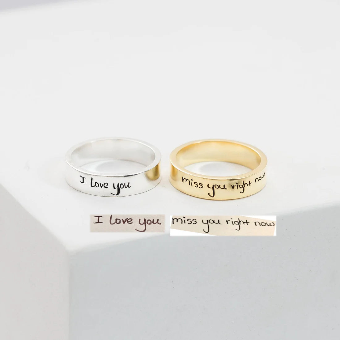 Two rings, one silver and one gold, with engraved messages on a white background.