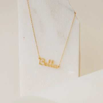 Gold 'Bella' necklace on a white marble surface