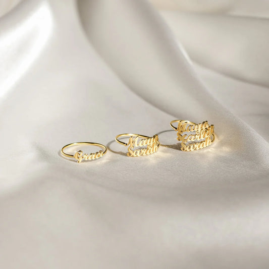Set of gold rings with engraved text on a white fabric background