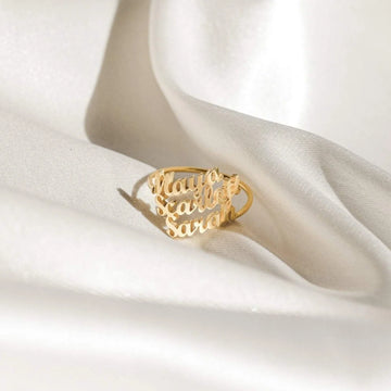 Gold ring with 'nayo calls sara' text on a white fabric background