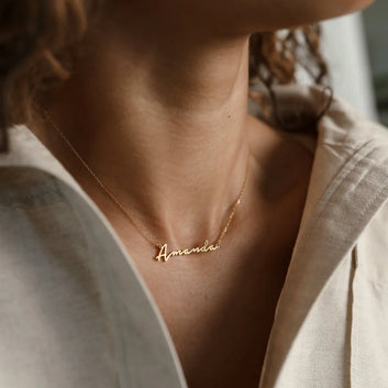 Gold necklace with 'Amanda' pendant on a person wearing a light-colored shirt.