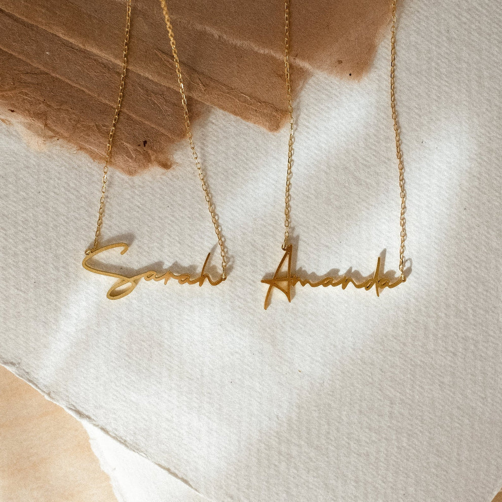 Two gold necklaces with 'Eternal Love' pendants on a textured white surface.