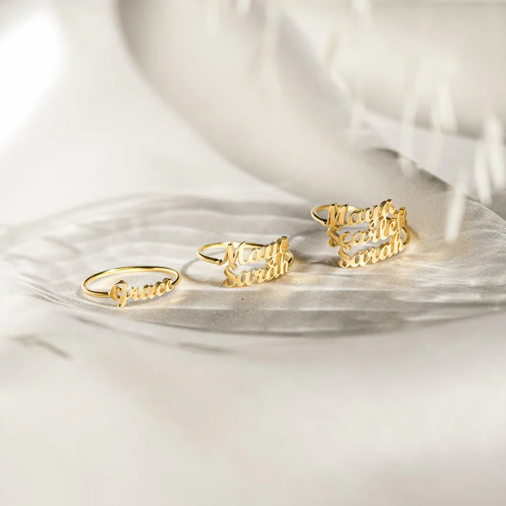 Gold rings with engraved text on a white fabric background