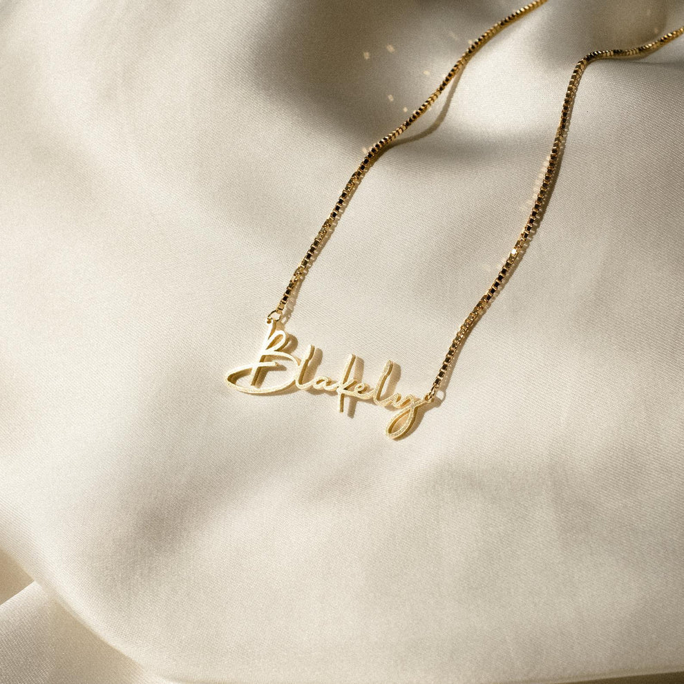 Gold necklace with 'Blakeley' pendant on a soft beige background