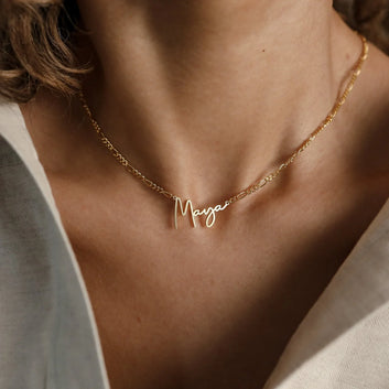 Gold necklace with 'Maya' pendant on a person's neck