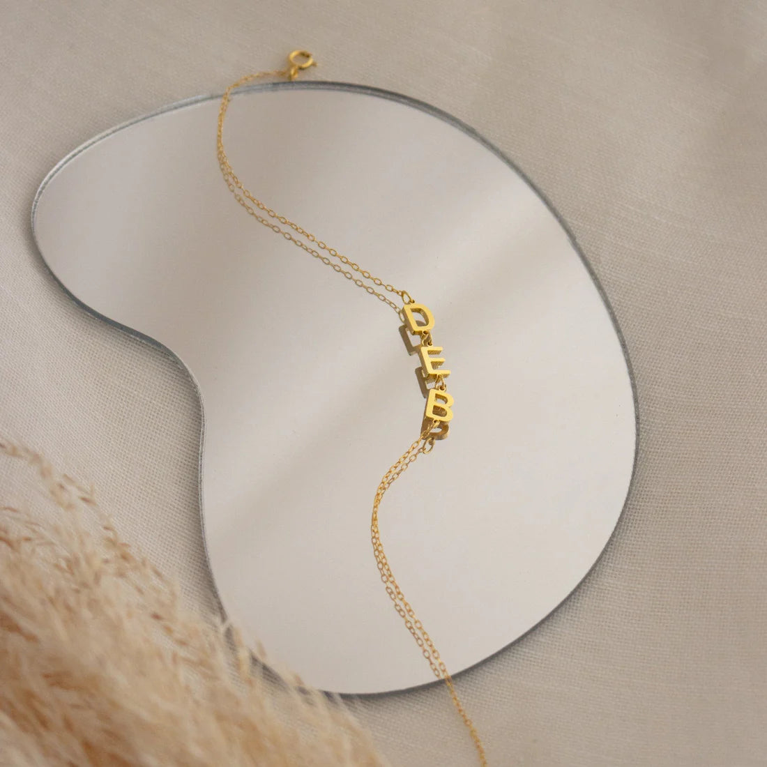 Gold bracelet with 'HEART' charm on a neutral background