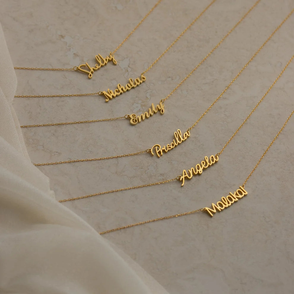 Gold name necklaces on a beige background