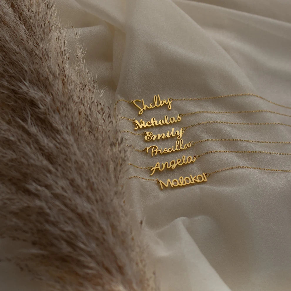 Gold name necklaces on a textured fabric background