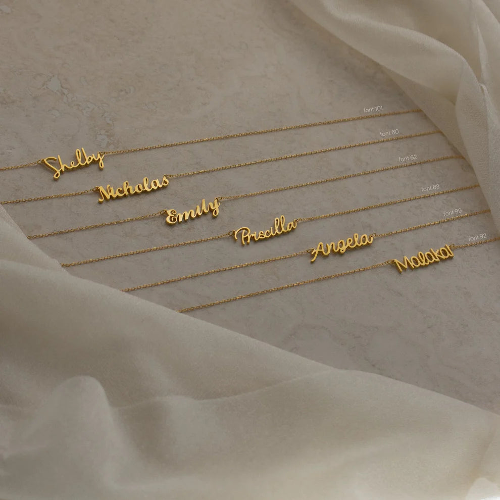 Gold name bracelets on a soft fabric background