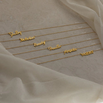 Gold name bracelets on a soft fabric background