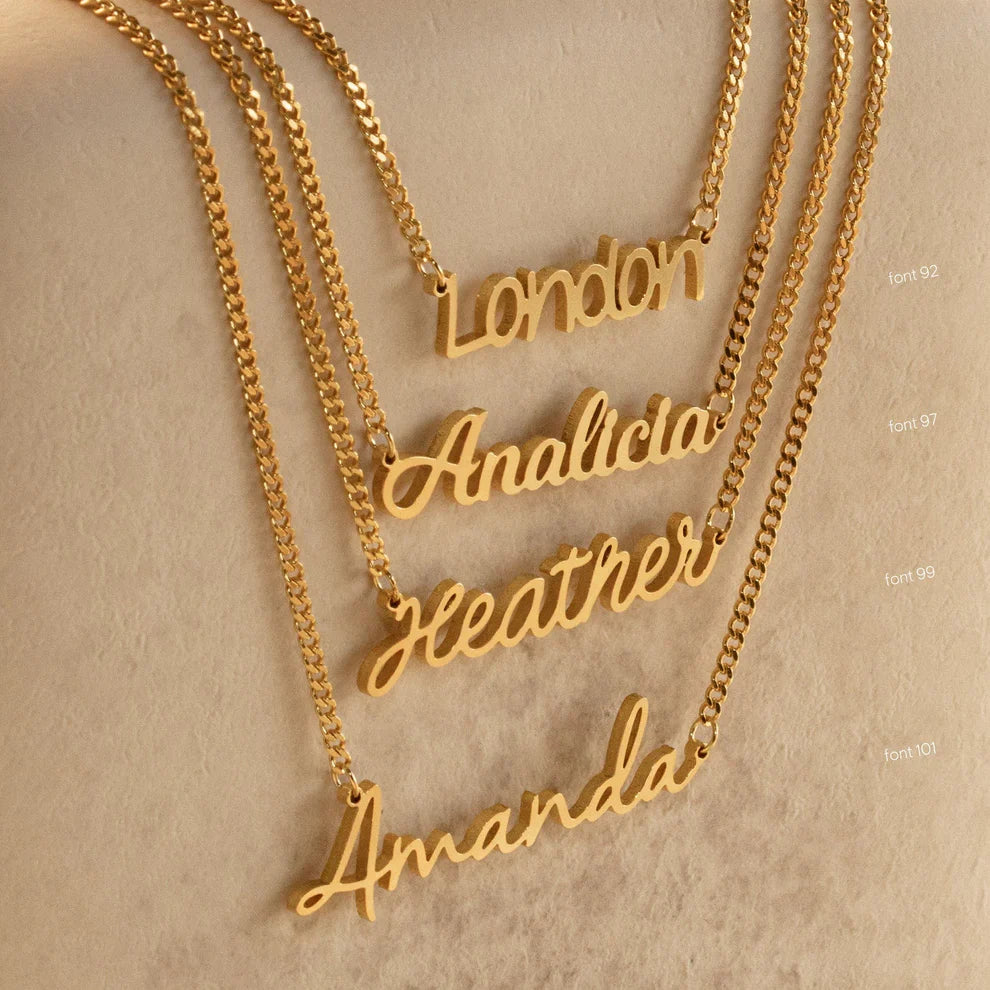 Gold name necklaces on a beige background
