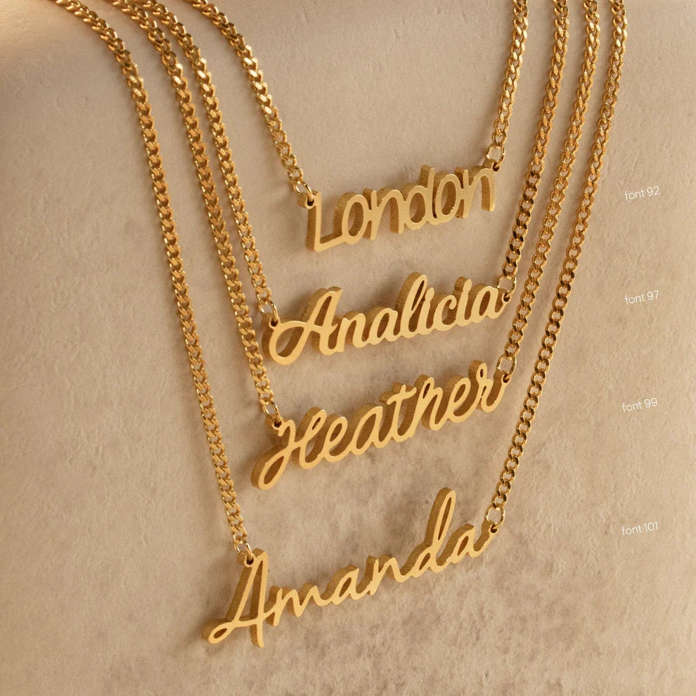 Gold name necklaces on a beige background