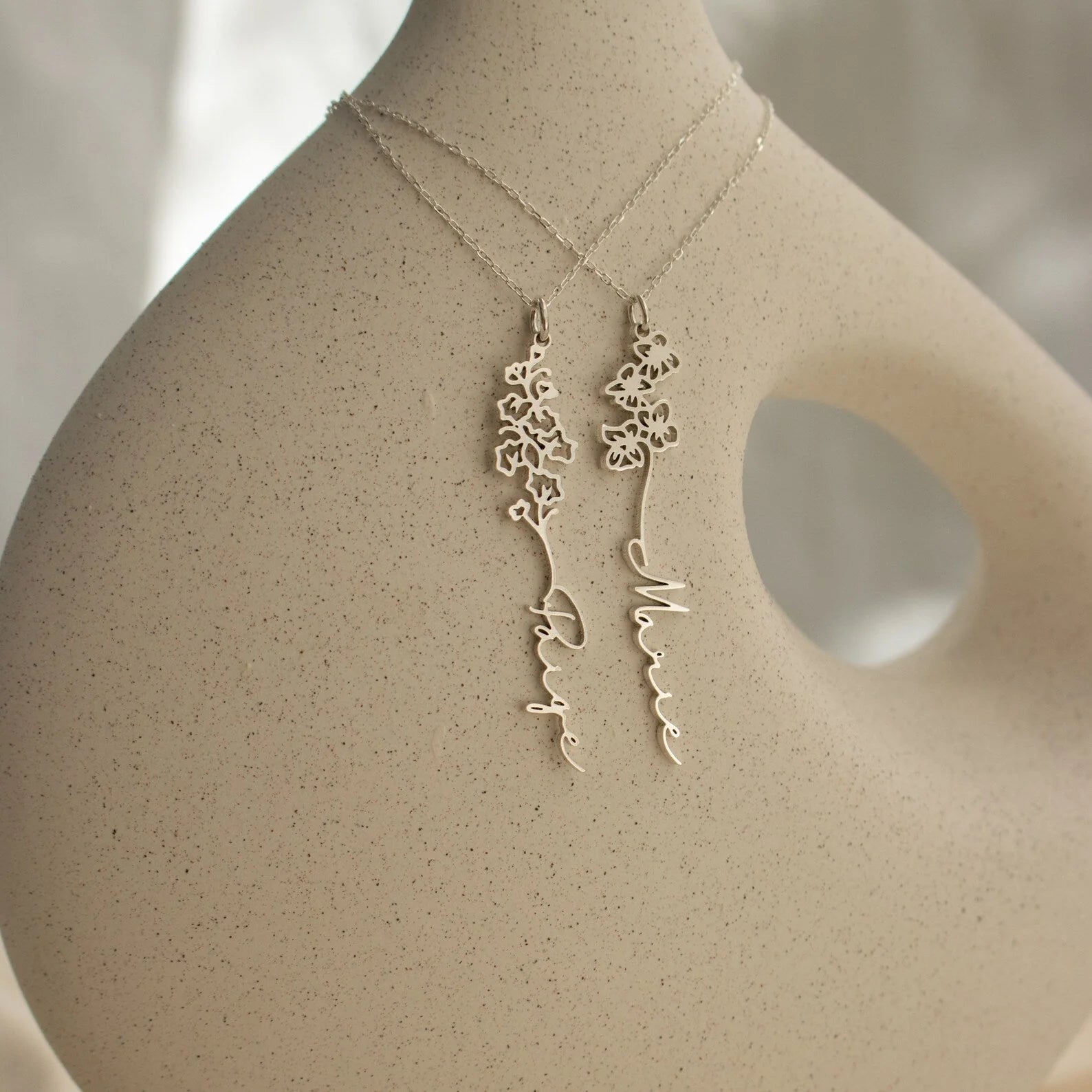 Gold necklace and earrings on a mannequin bust with a neutral background