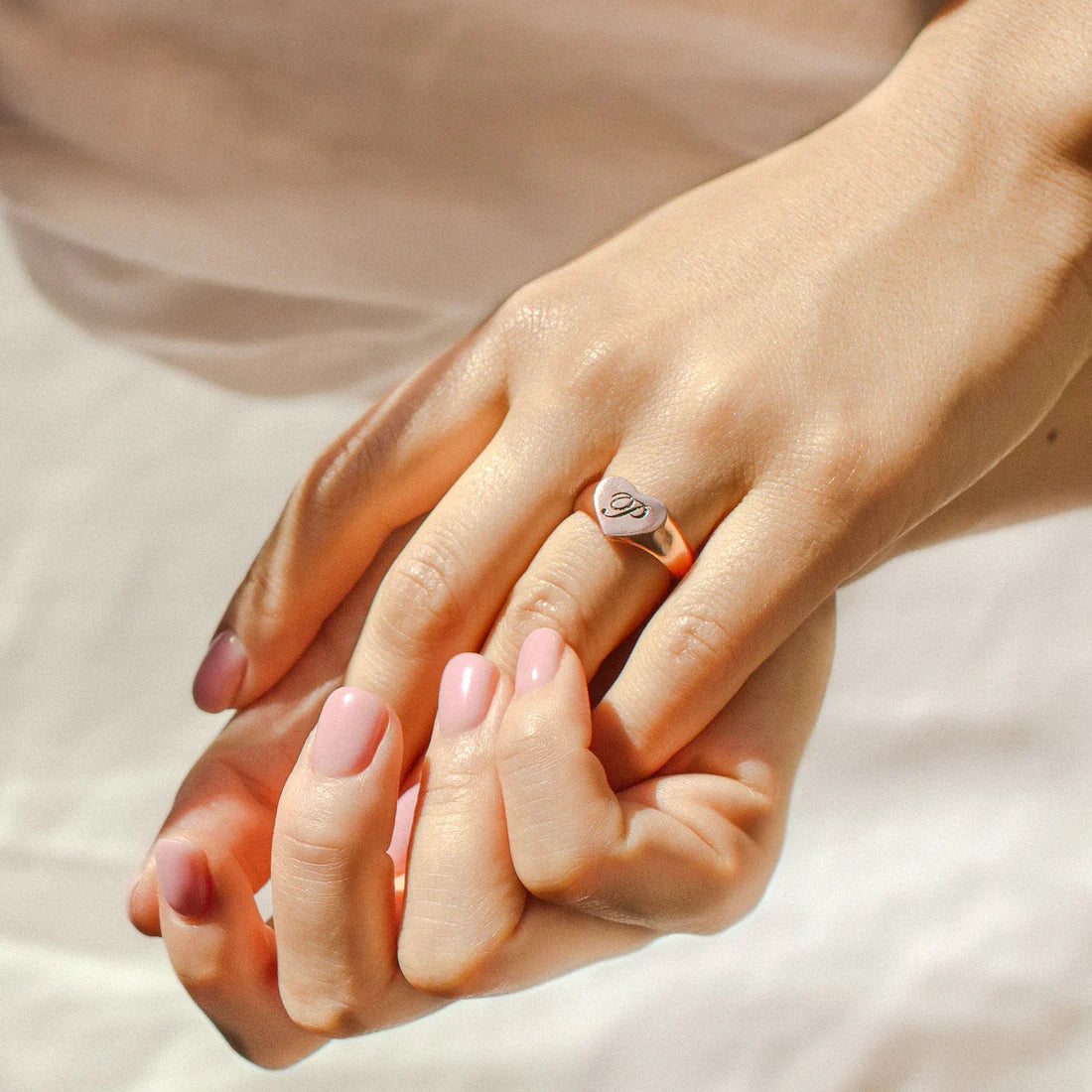 Close-up of two hands with a ring on a soft beige background
