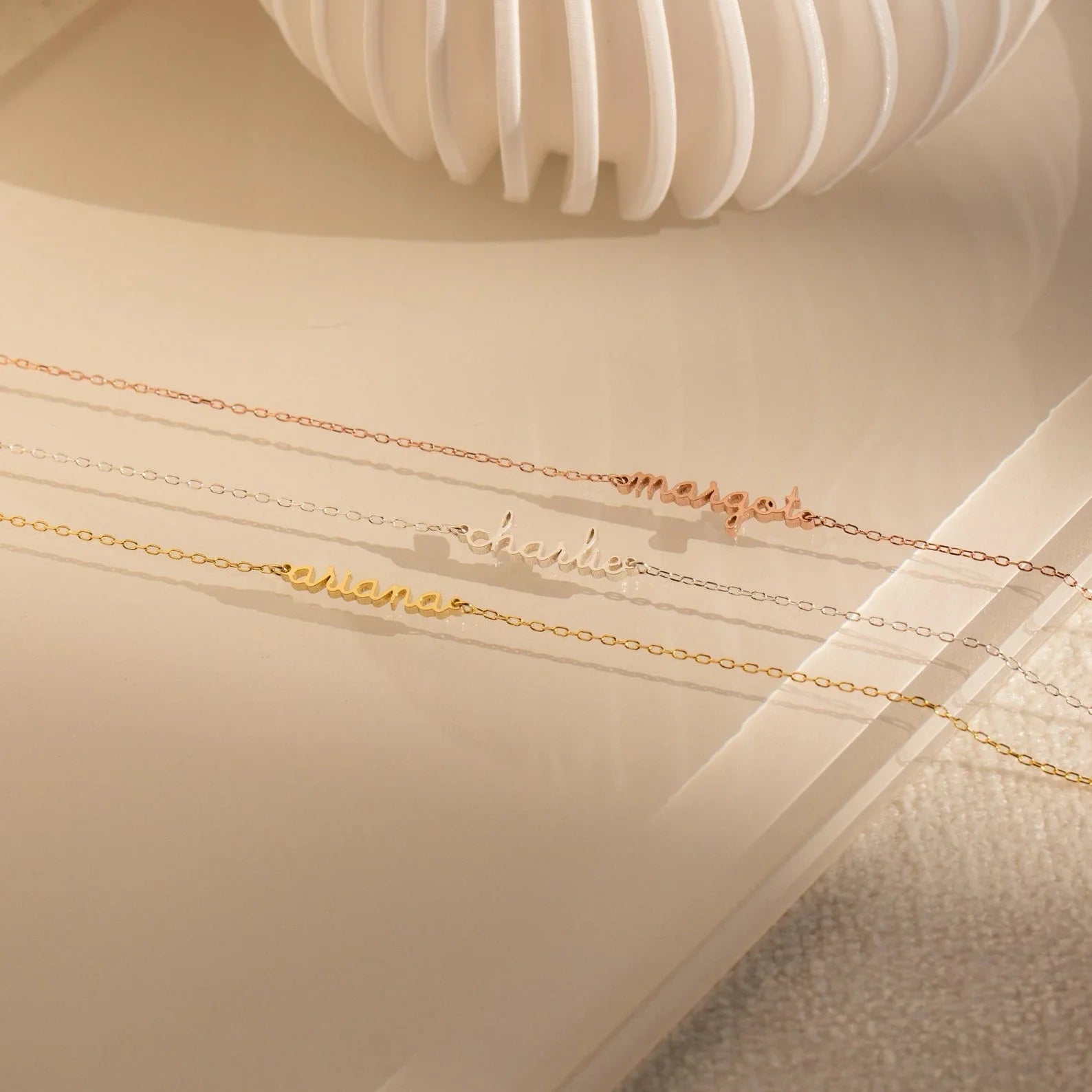 Gold necklaces with engraved names on a light wooden surface