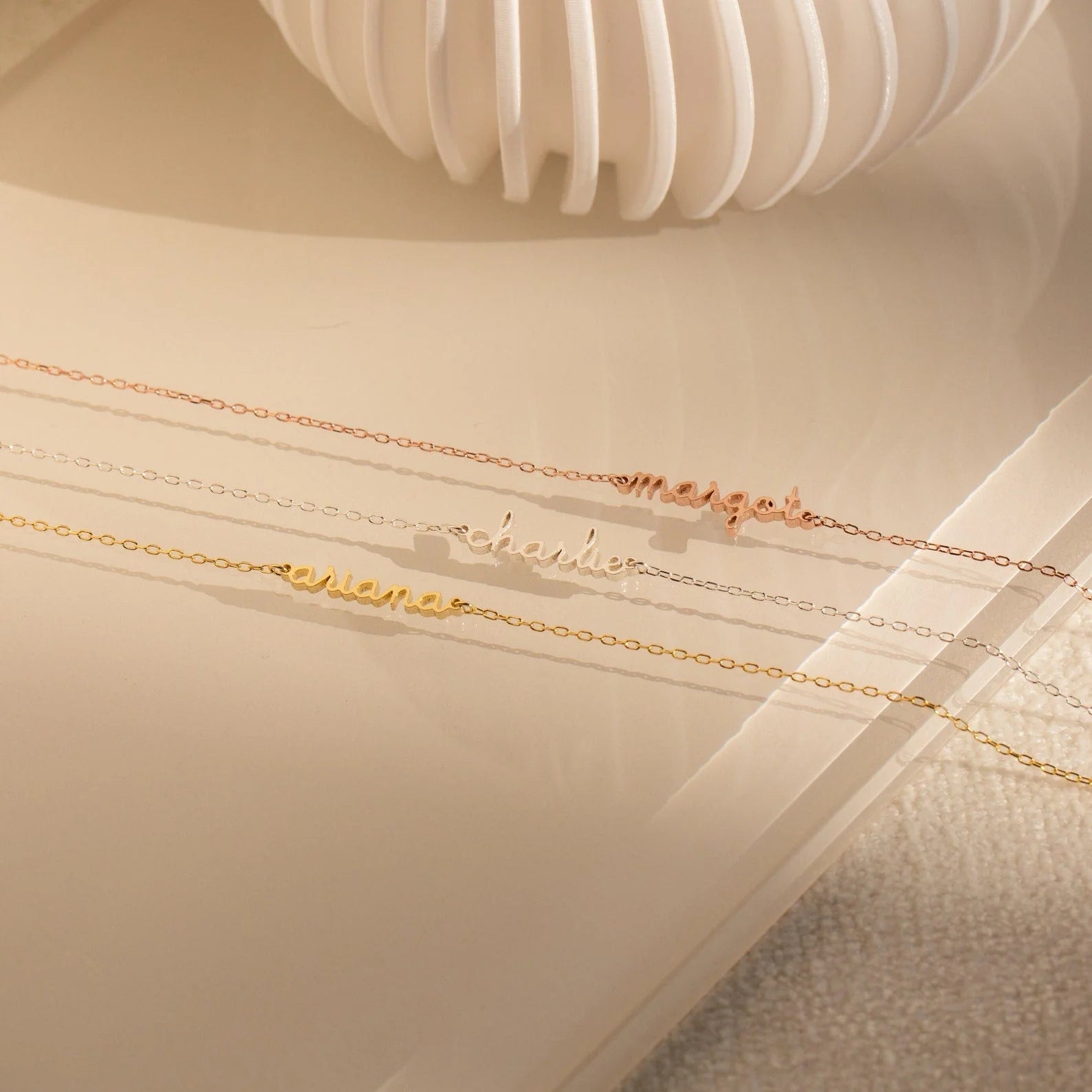 Gold necklaces with engraved names on a light wooden surface