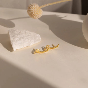 Gold necklace on a textured beige surface with a decorative flower.