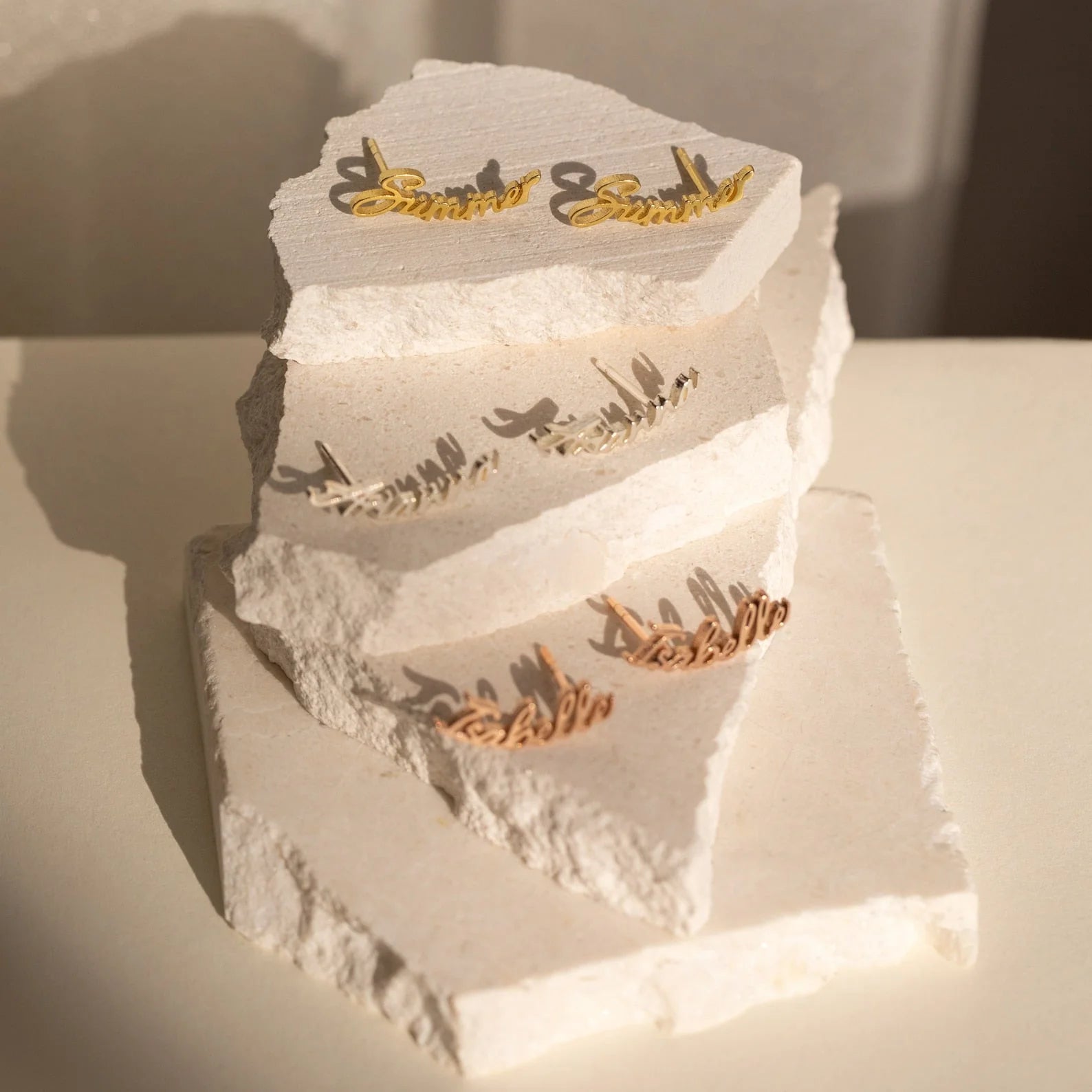 Three-tiered white wedding cake with gold 'Samantha & Samantha' topper on a neutral background