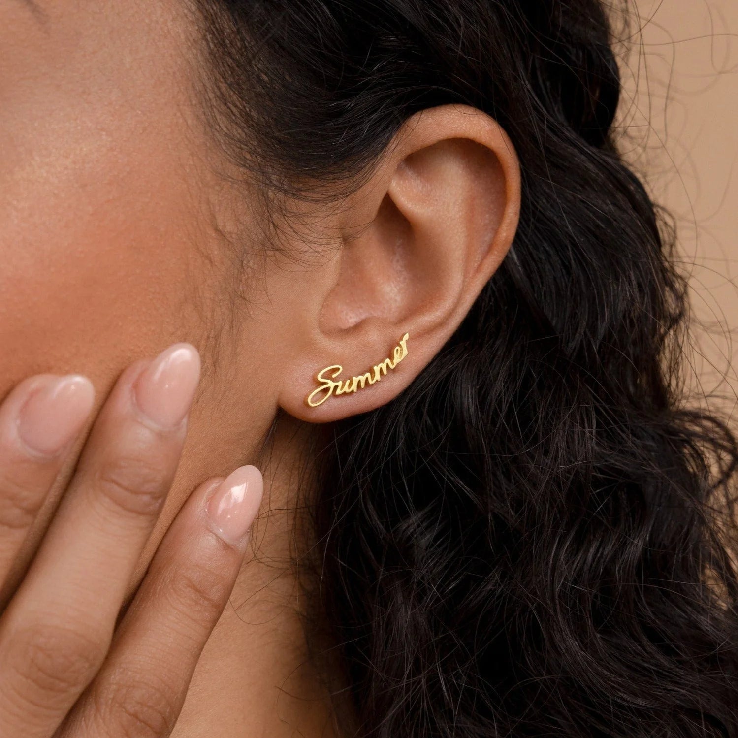 Gold 'Summer' earring worn by a person with dark hair.