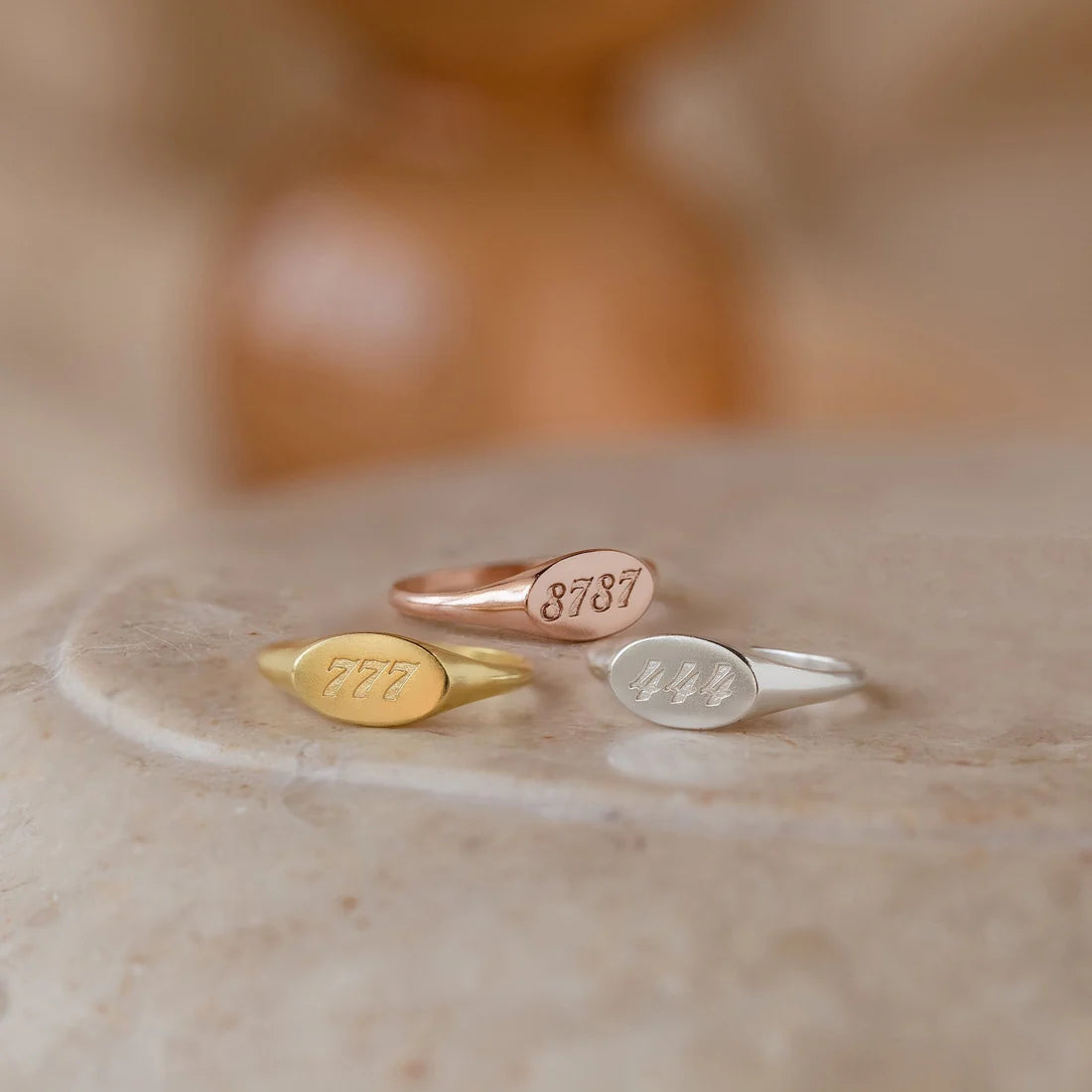 Three gold rings with engraved numbers on a marble surface