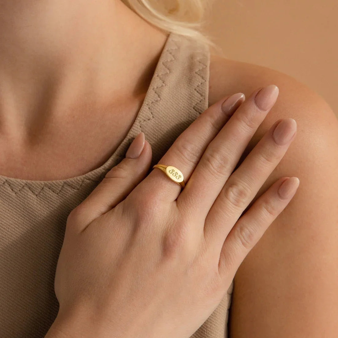 Close-up of a hand wearing a gold ring with a blurred background