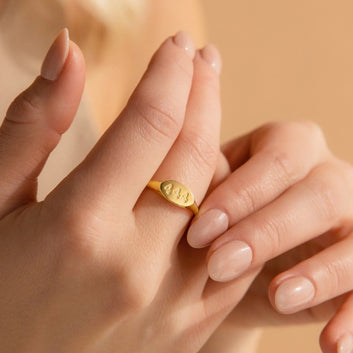 Close-up of a hand wearing a gold ring with a blurred background