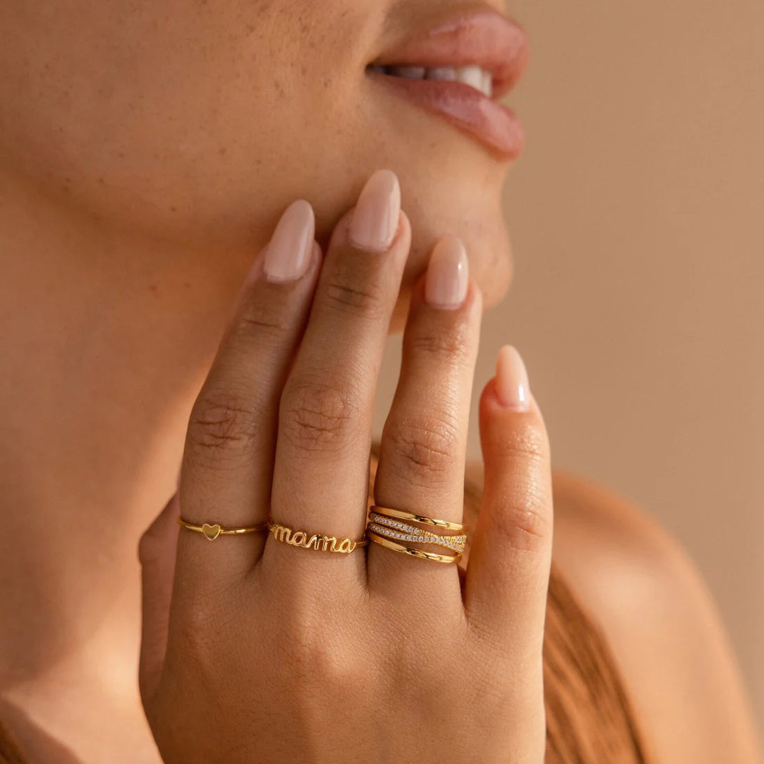 Close-up of a hand wearing gold rings with a neutral background