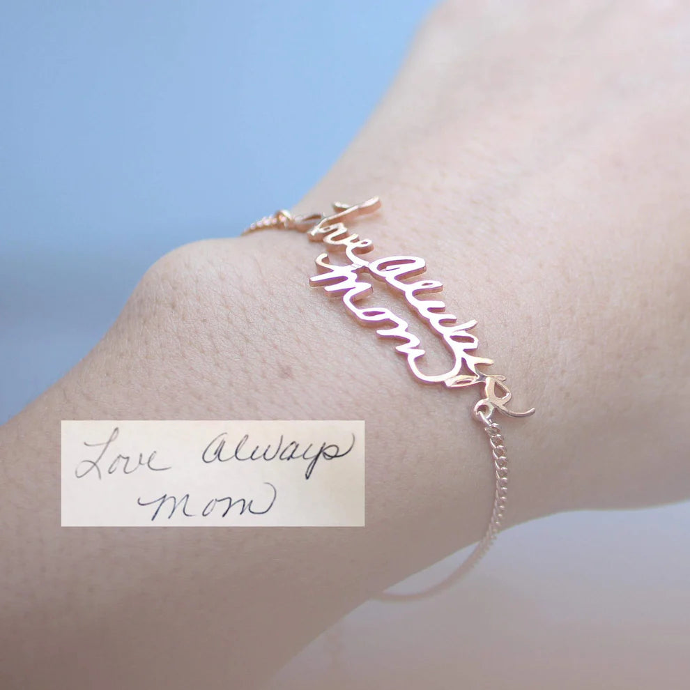 Rose gold bracelet with 'love always mom' on wrist against a light background