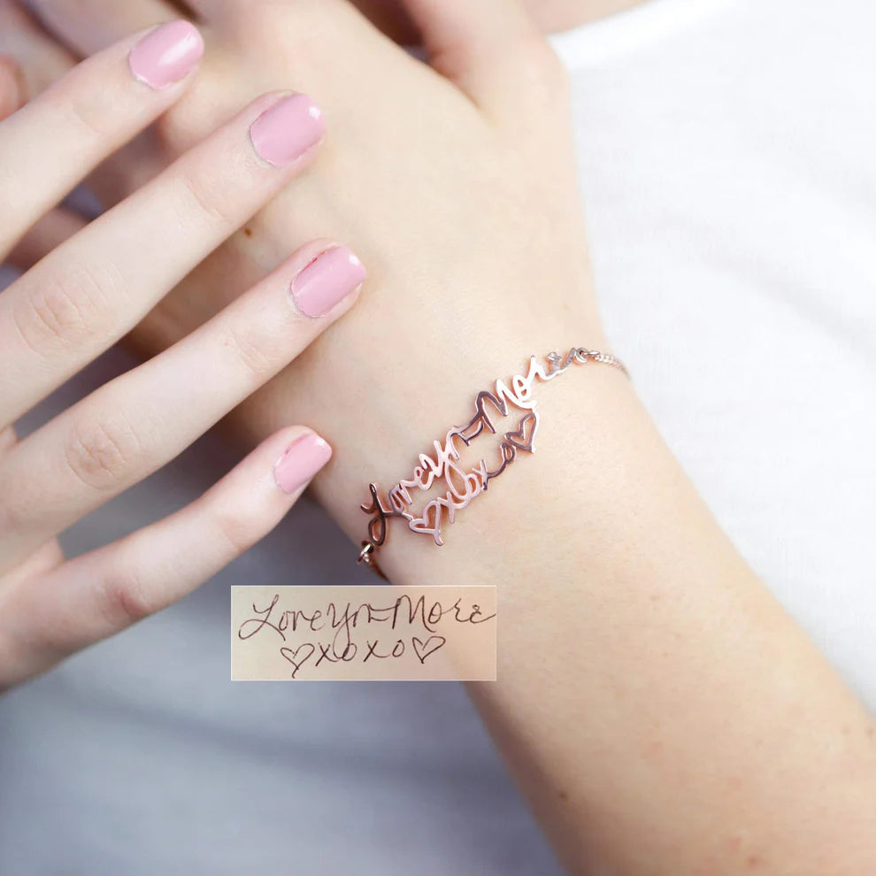 Rose gold bracelet on a wrist with pink nail polish and a handwritten note.