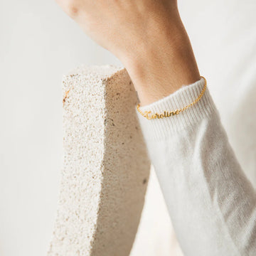 Gold bracelet on a person's wrist with a blurred background