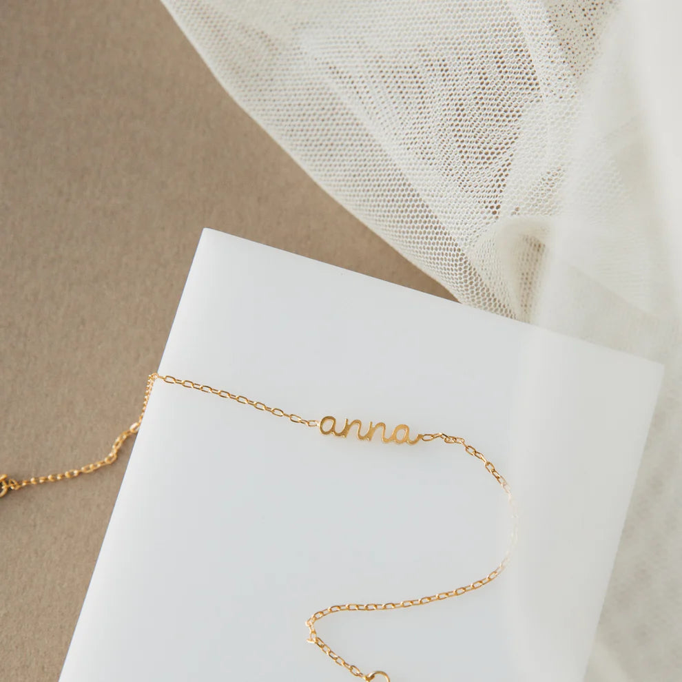 Gold bracelet with 'anna' engraving on a white card