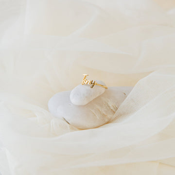 Gold ring with 'amy' engraving on a white surface