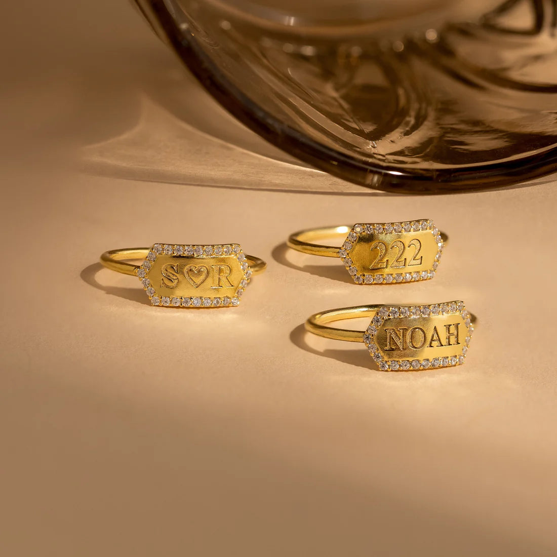 Three gold rings with engraved text on a beige surface