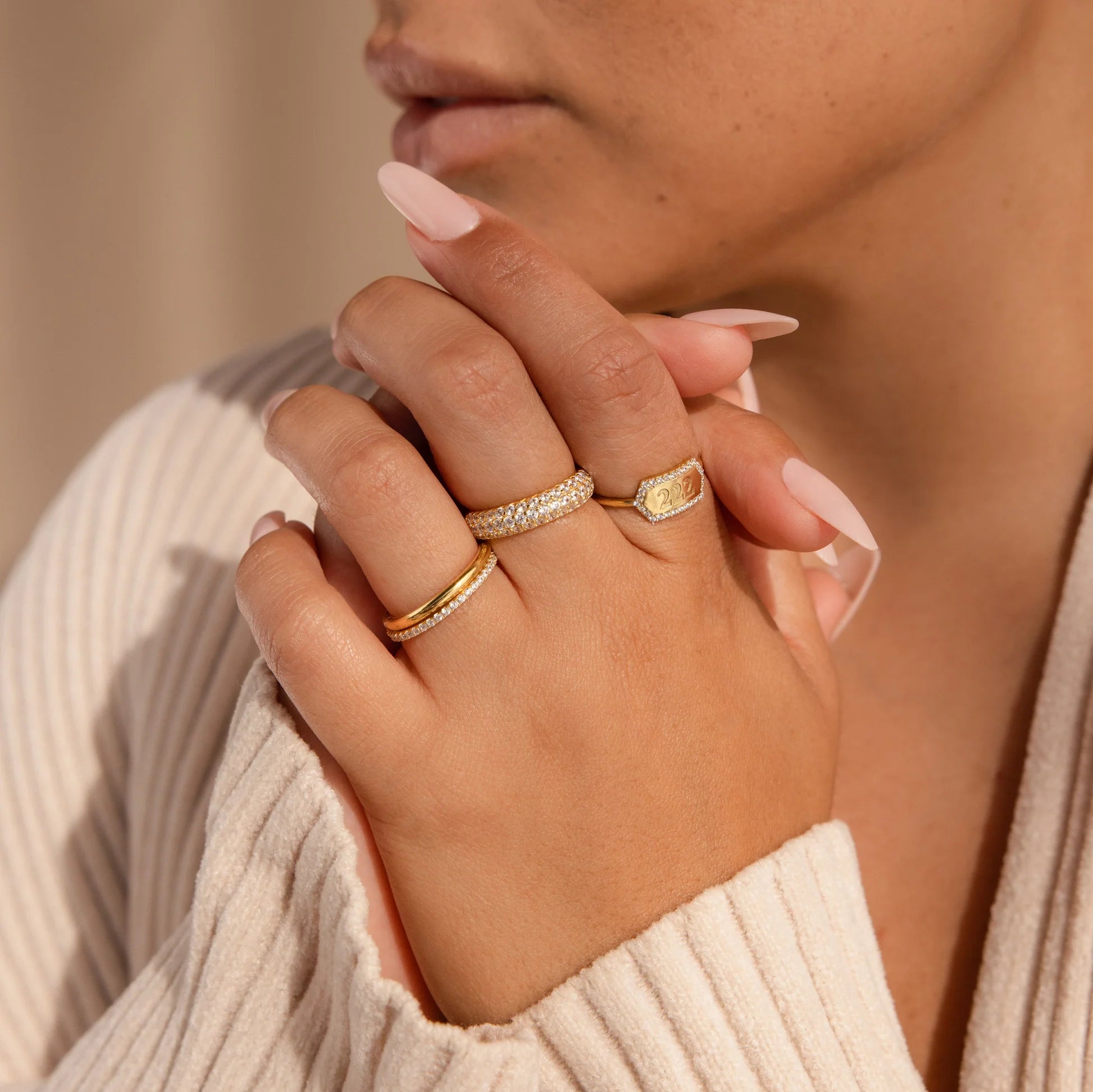 Close-up of a hand wearing multiple rings with a neutral background